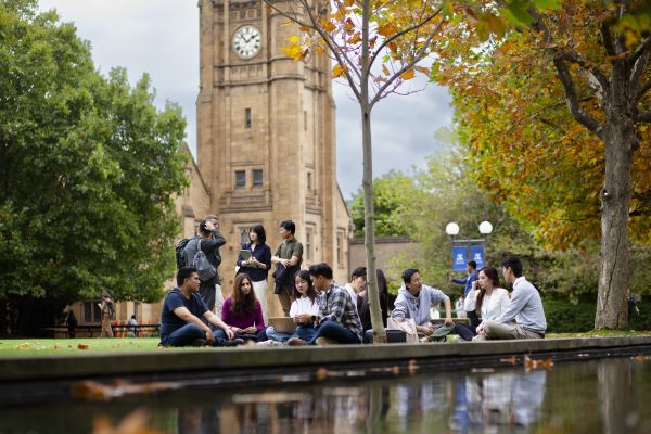 Group of students sitting outside on grass chatting